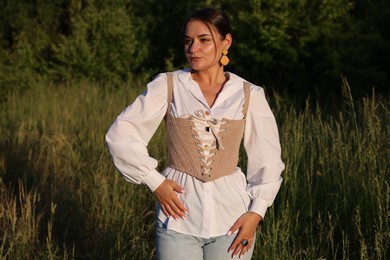 Beautiful woman in stylish corset posing outdoors