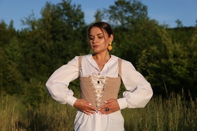 Beautiful woman in stylish corset posing outdoors