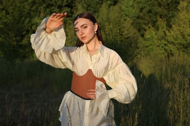 Photo of Beautiful woman in stylish corset posing outdoors