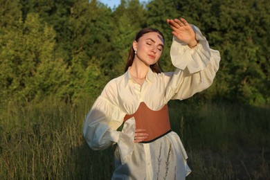 Beautiful woman in stylish corset posing outdoors