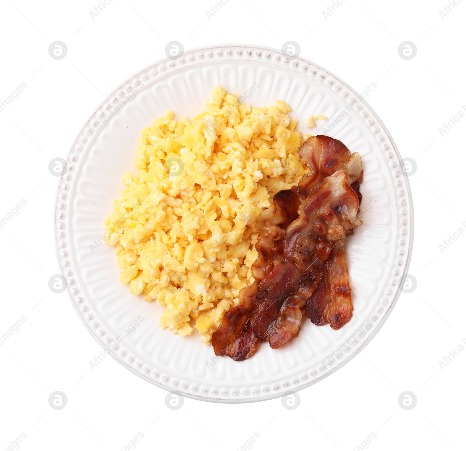 Photo of Delicious scrambled eggs with bacon on plate isolated on white, top view