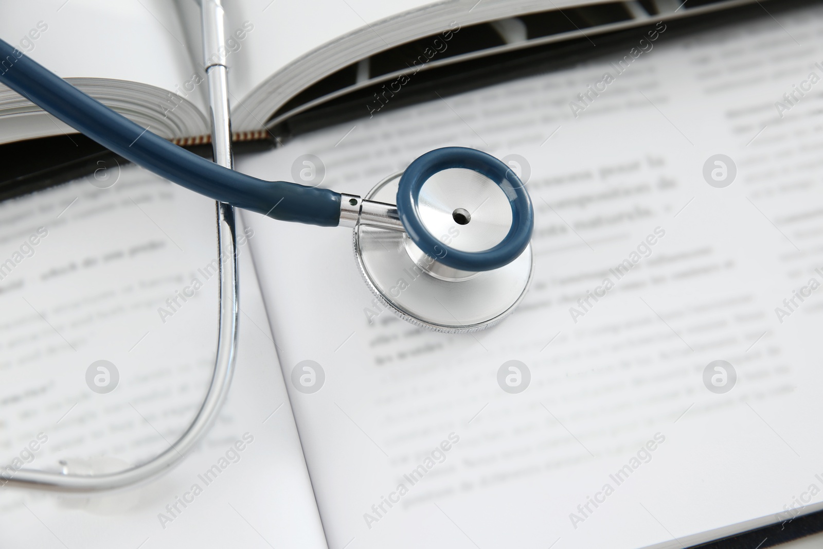 Photo of One medical stethoscope and books on table, above view