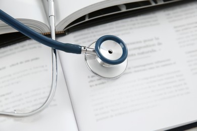 One medical stethoscope and books on table, above view