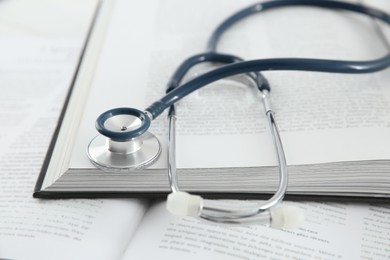 Photo of One new medical stethoscope and books on table, closeup