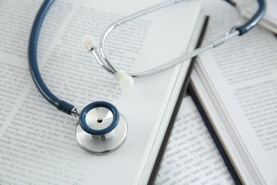 Photo of One new medical stethoscope and books on table, closeup