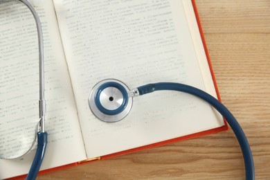 Photo of One new medical stethoscope on wooden table, top view