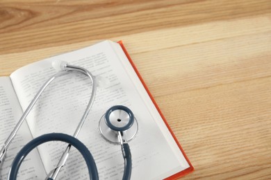 One new medical stethoscope on wooden table, closeup