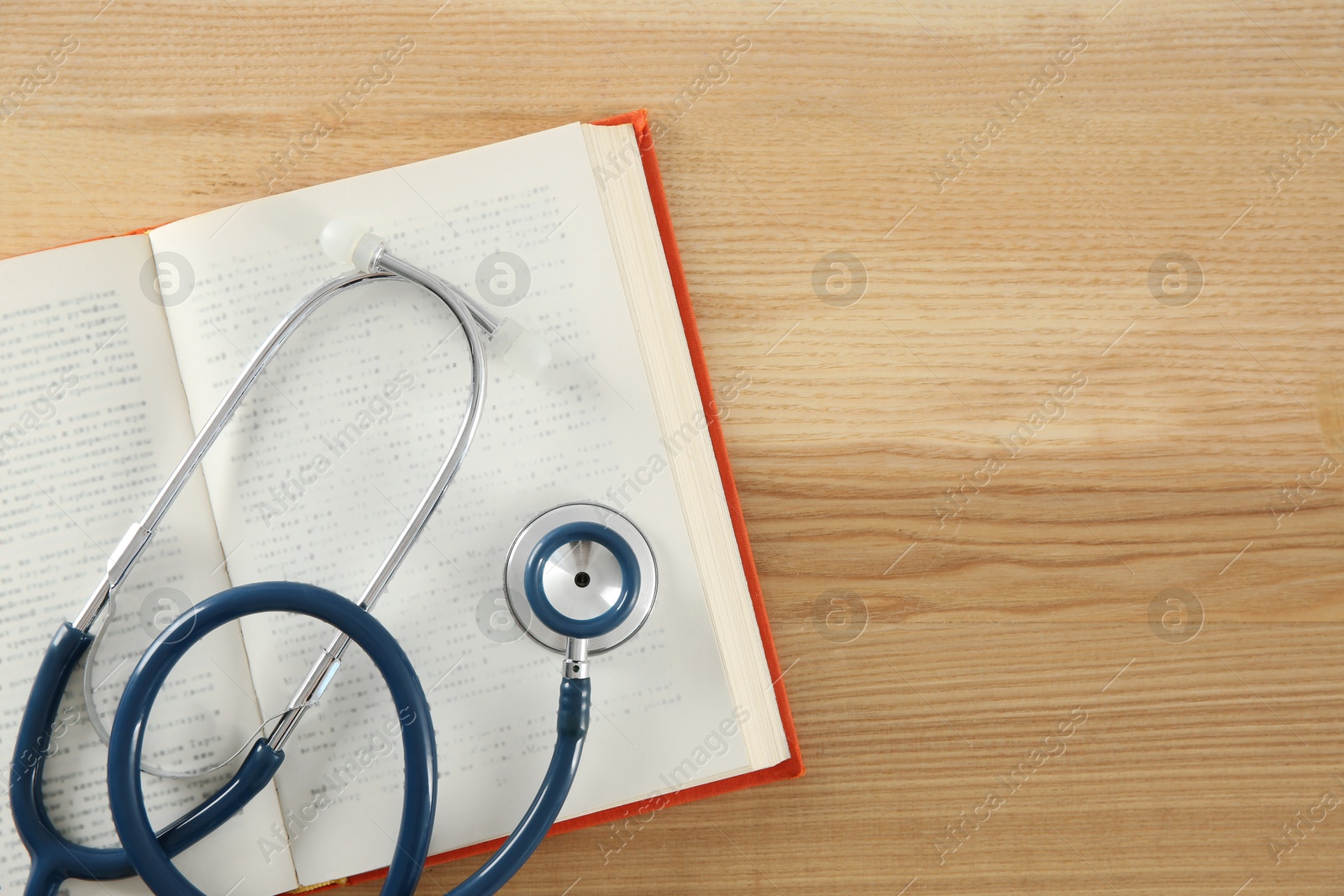 Photo of One new medical stethoscope on wooden table, top view. Space for text