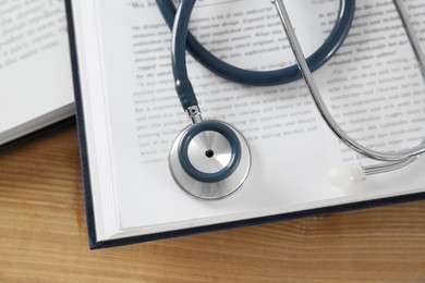 One new medical stethoscope and books on wooden table, top view