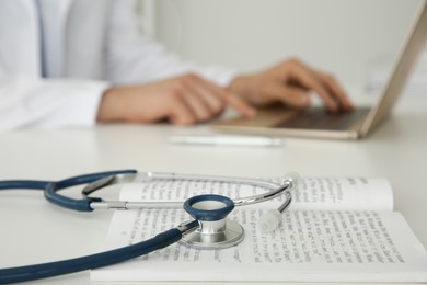 Photo of Doctor at white table in hospital, focus on medical stethoscope