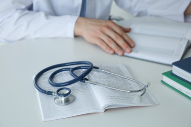 Photo of Doctor at white table in hospital, focus on medical stethoscope