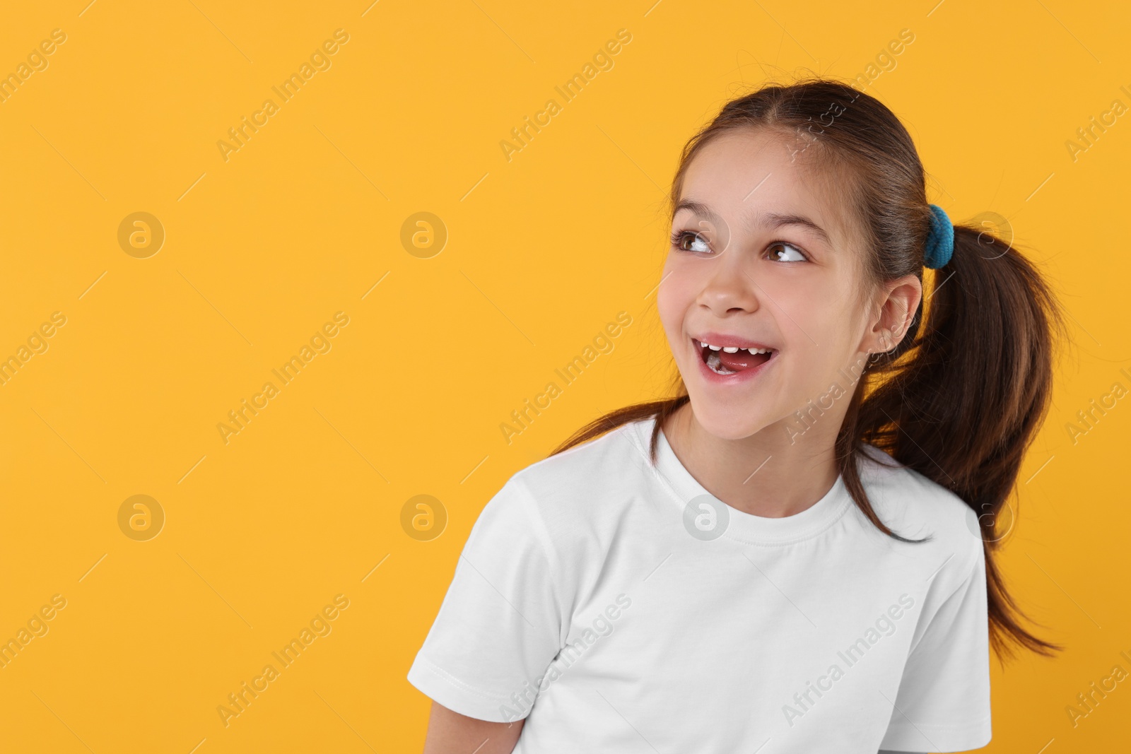 Photo of Portrait of happy girl on orange background, space for text