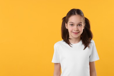 Portrait of beautiful girl on orange background, space for text