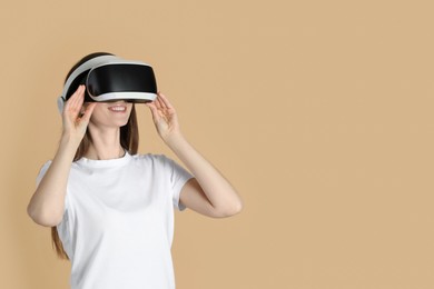 Photo of Smiling woman using virtual reality headset on beige background, space for text
