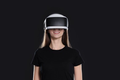 Photo of Smiling woman using virtual reality headset on black background