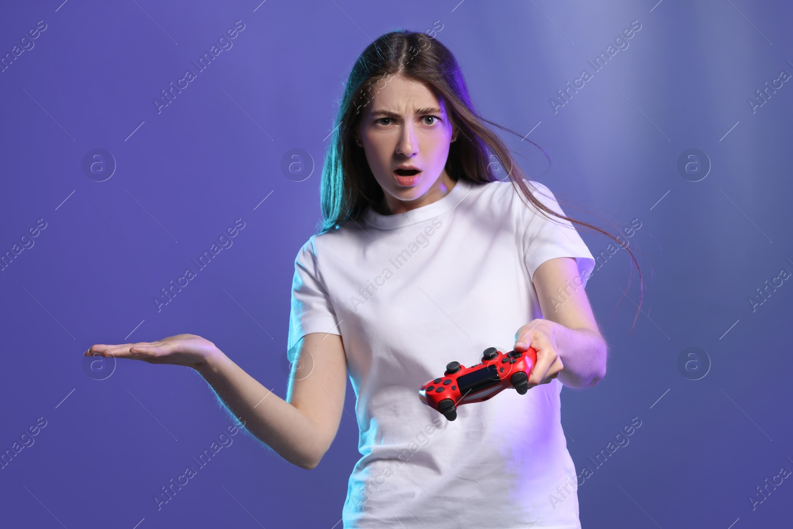 Photo of Surprised woman playing video games with controller on violet background