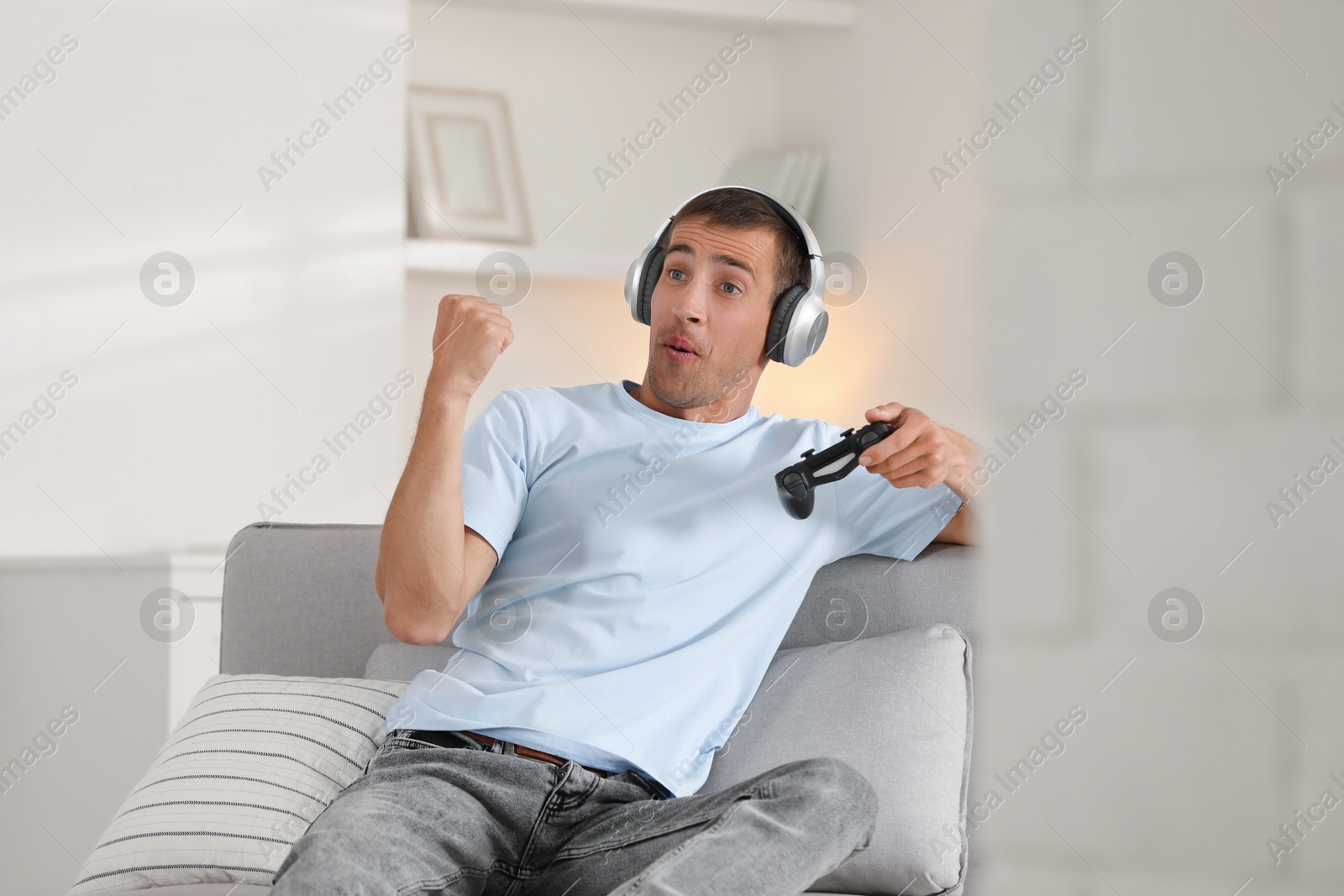 Photo of Happy man in headphones playing video games with joystick at home