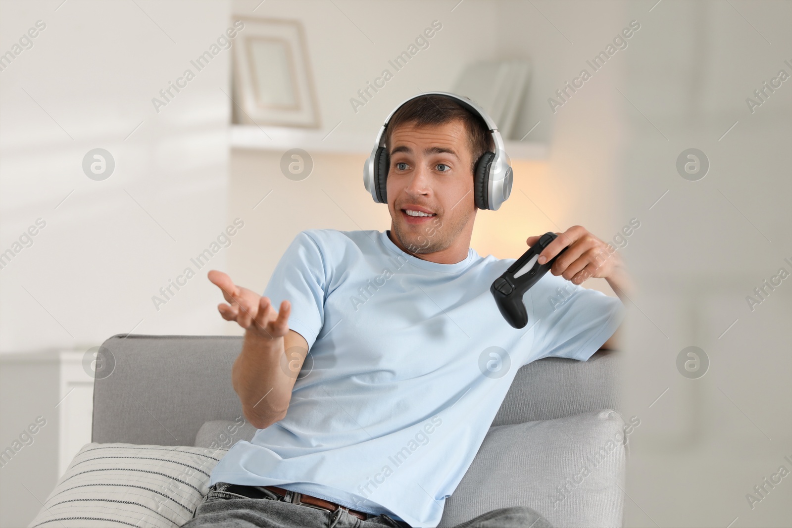 Photo of Man in headphones playing video games with joystick at home