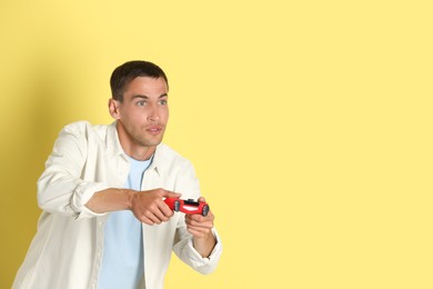Photo of Man playing video games with controller on yellow background, space for text