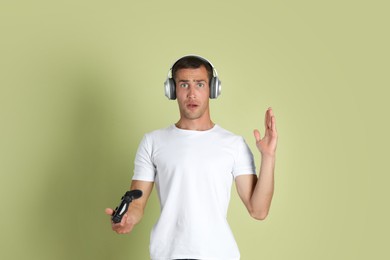 Surprised man controller on light green background