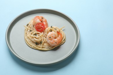 Photo of Heart made of tasty spaghetti, tomato, shrimps and cheese on light blue background. Space for text