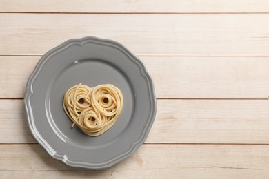 Photo of Heart made of tasty spaghetti on wooden table, top view. Space for text