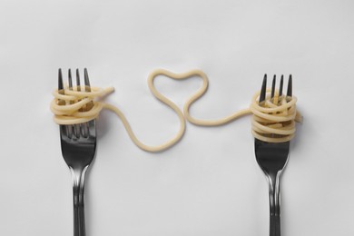 Photo of Heart made of tasty spaghetti and forks isolated on white, top view