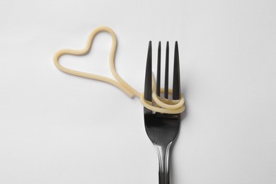 Photo of Heart made of tasty spaghetti and fork isolated on white, top view