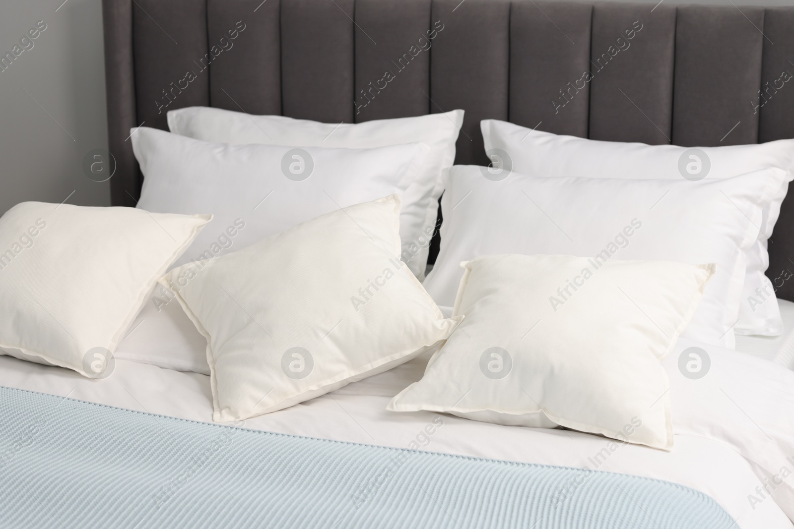 Photo of Many soft pillows on bed at home