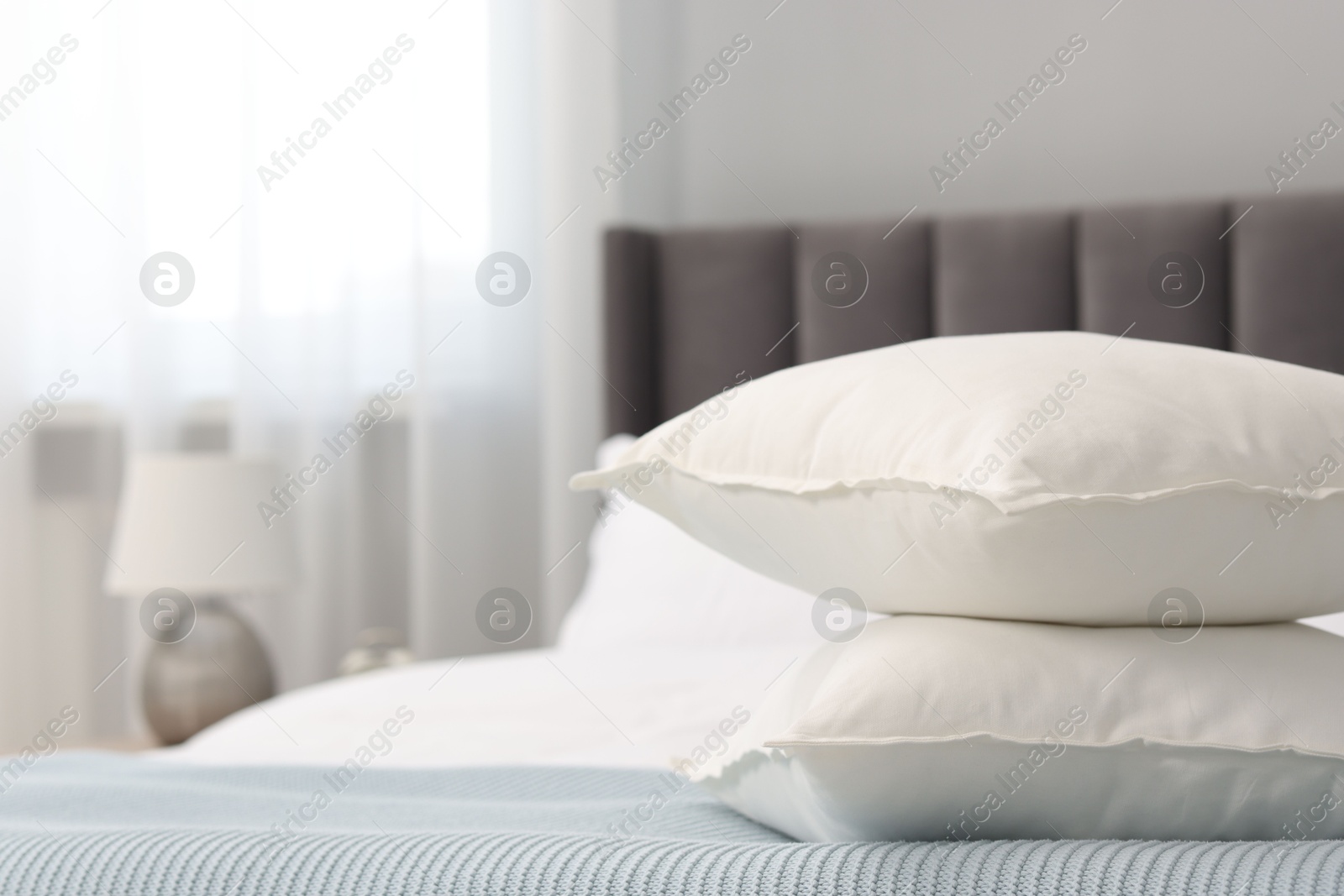 Photo of Many soft pillows on bed at home