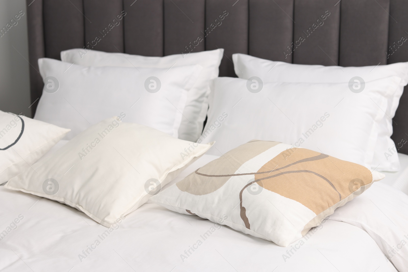 Photo of Many soft pillows on bed at home