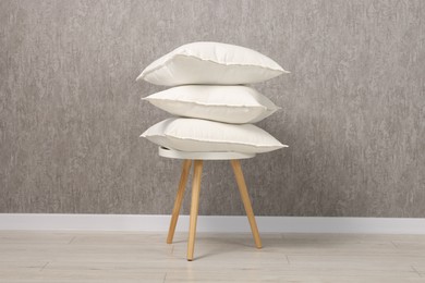 Photo of Many soft pillows on chair near grey wall