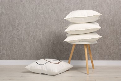 Many soft pillows on chair near grey wall. Space for text