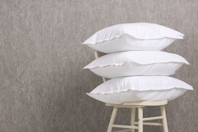 Photo of Many soft pillows on chair near grey wall. Space for text