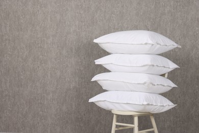 Photo of Many soft pillows on chair near grey wall. Space for text