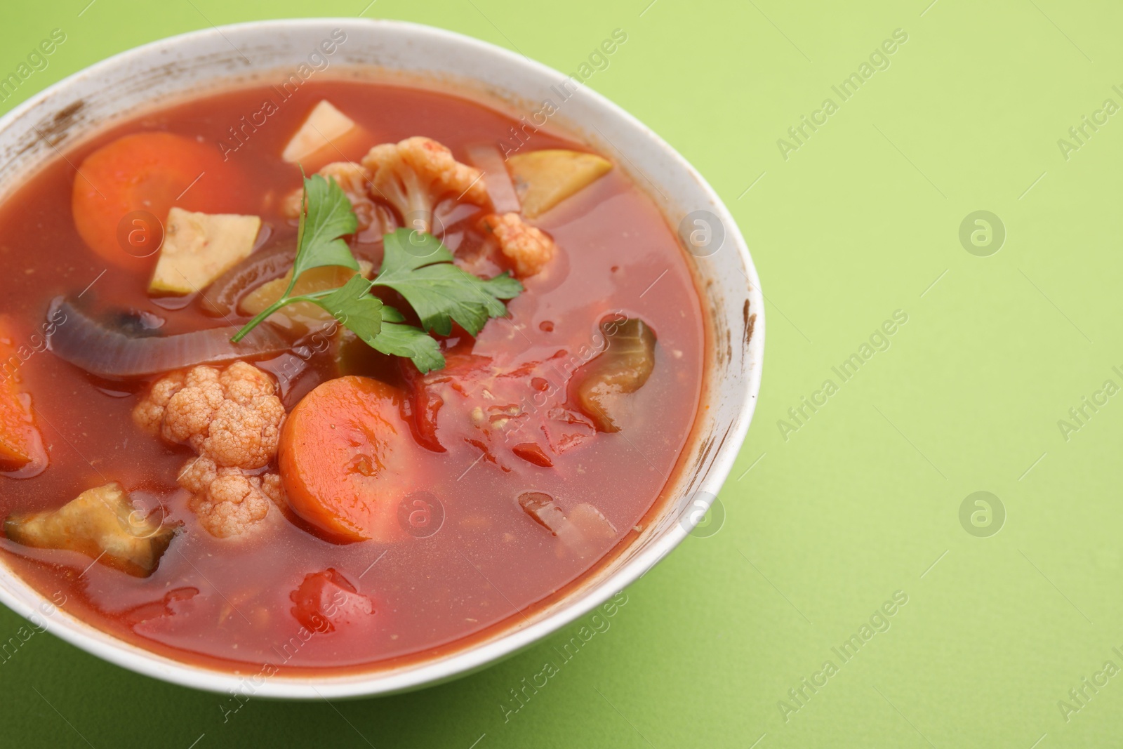 Photo of Delicious homemade stew in bowl on green background, closeup