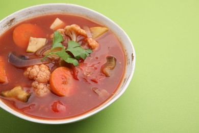 Delicious homemade stew in bowl on green background, closeup