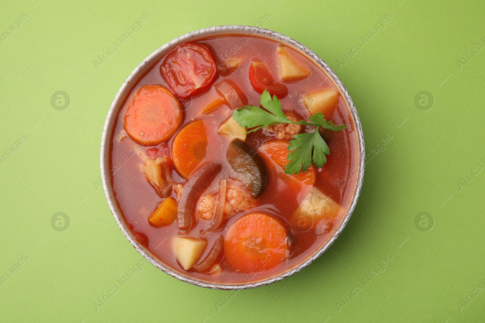 Photo of Delicious homemade stew in bowl on green background, top view