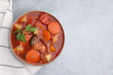 Photo of Delicious homemade stew in bowl on light table, top view. Space for text