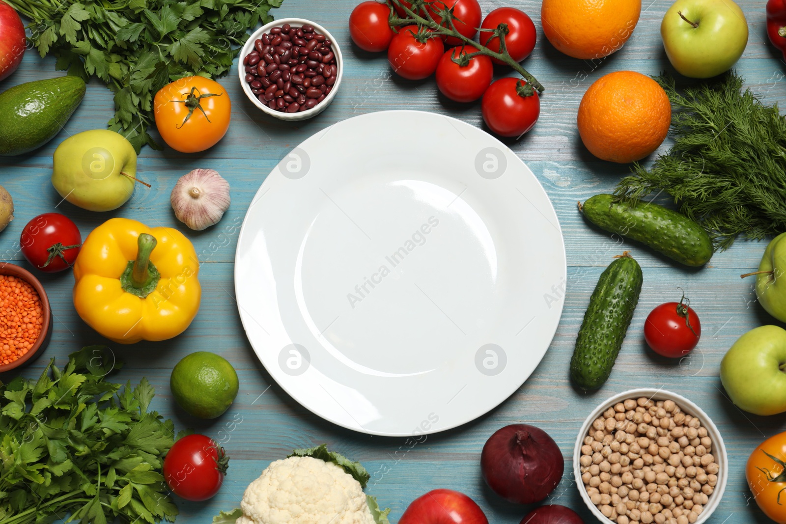 Photo of Different vegetarian products and plate on light blue wooden table, top view