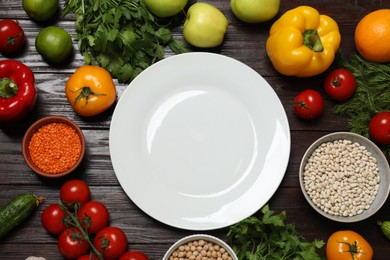 Photo of Different vegetarian products and plate on wooden table, top view