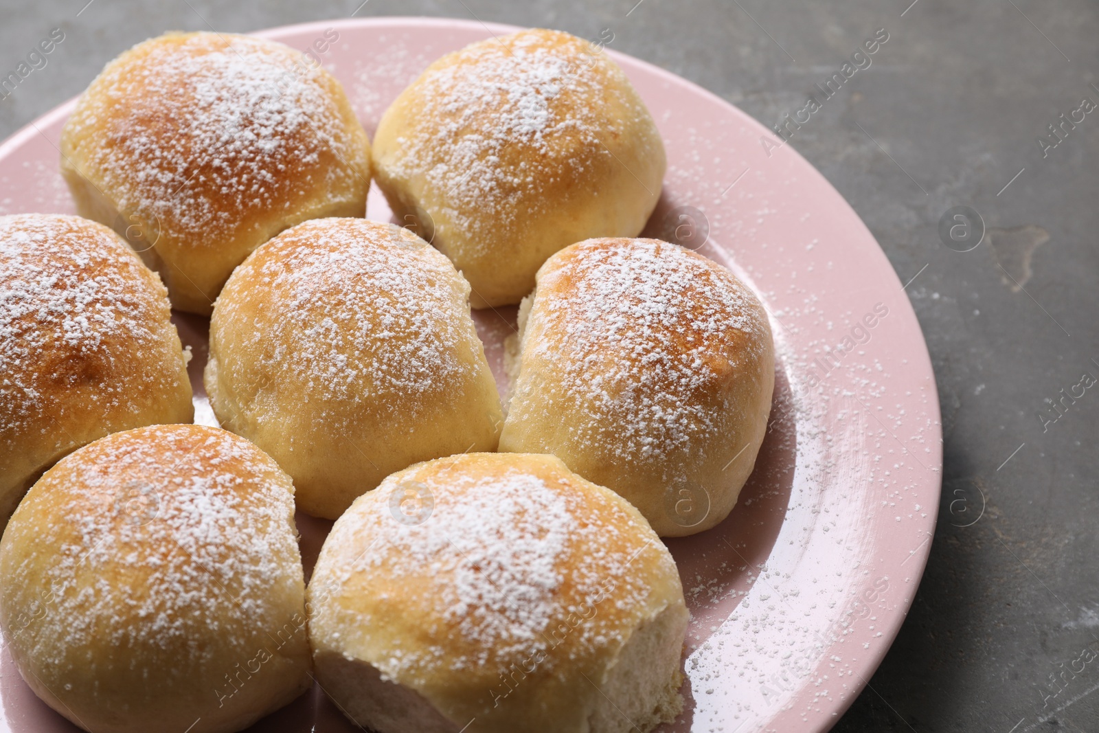 Photo of Delicious dough balls with powdered sugar on grey table, closeup