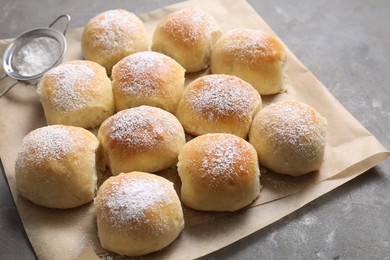 Delicious dough balls with powdered sugar and sieve on grey table