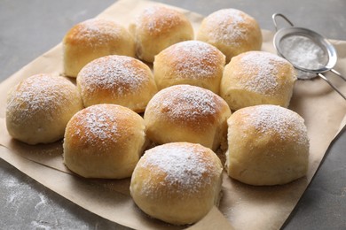 Delicious dough balls with powdered sugar and sieve on grey table