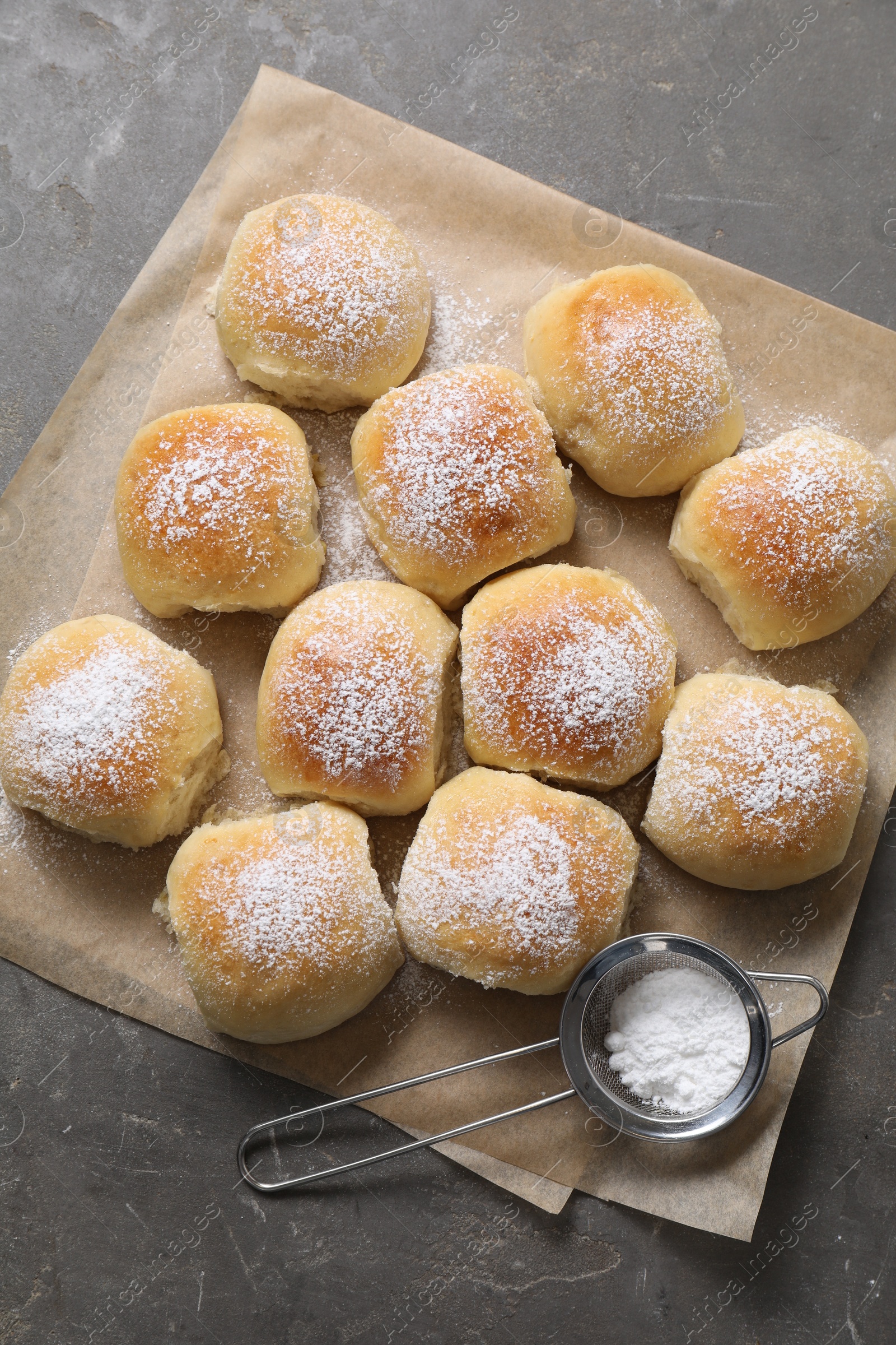 Photo of Delicious dough balls with powdered sugar and sieve on grey table, top view