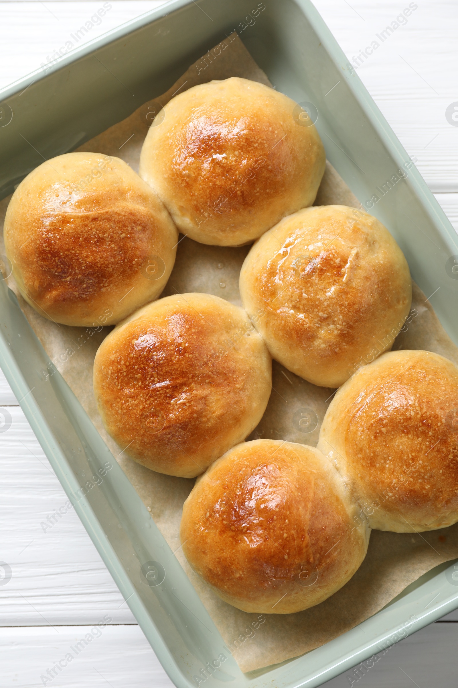 Photo of Delicious dough balls in baking dish on white wooden table, top view