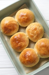 Delicious dough balls in baking dish on white wooden table, top view