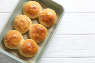 Photo of Delicious dough balls in baking dish on white wooden table, top view. Space for text