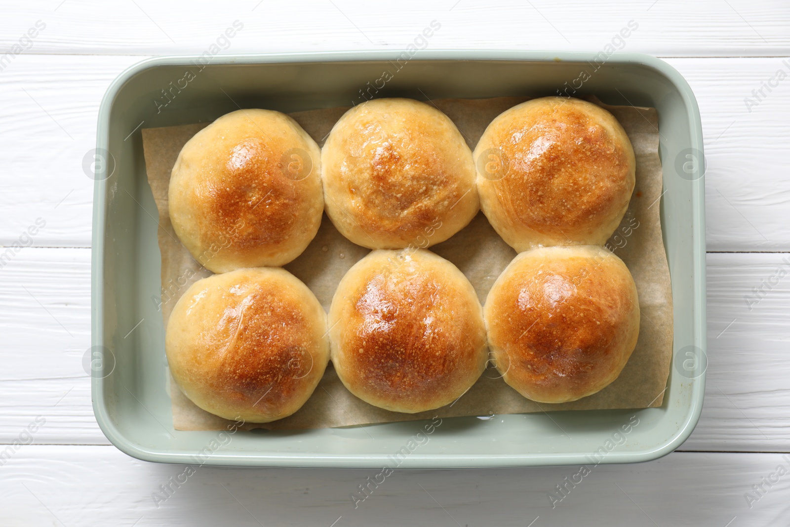 Photo of Delicious dough balls in baking dish on white wooden table, top view