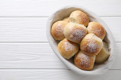 Delicious dough balls in basket on white wooden table, top view. Space for text